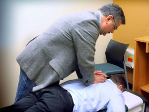 Image of a chiropractor adjusting the back of a patient 